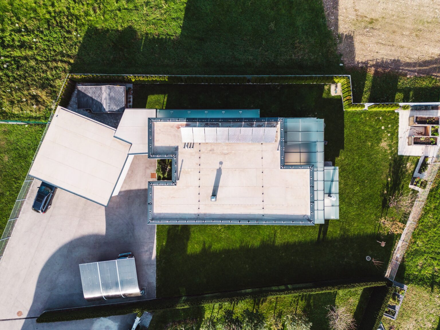 Top down view at the lot of a modern family home with flat rooftop and solar panels on it